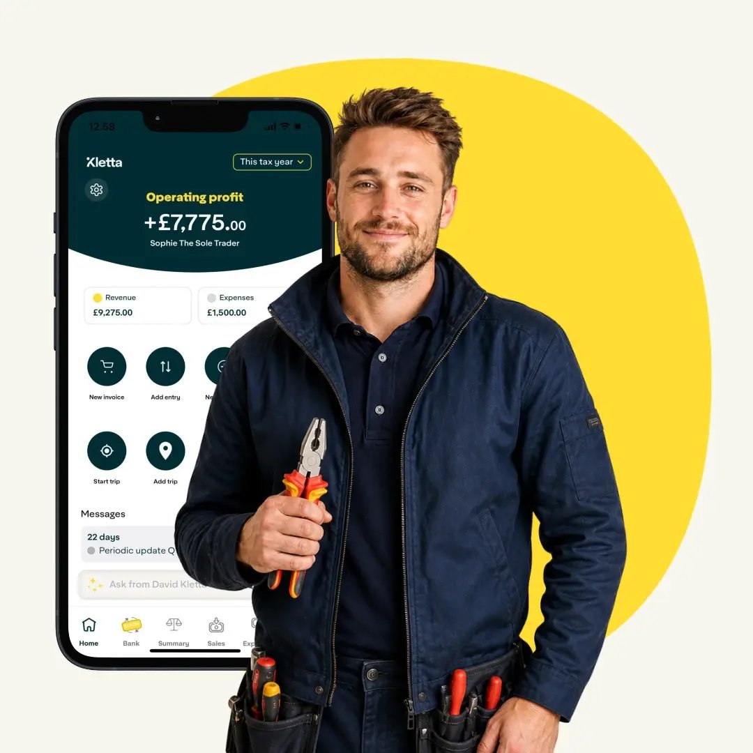 Smiling UK sole trader electrician in navy workwear holding insulated pliers, standing against a clean light background.